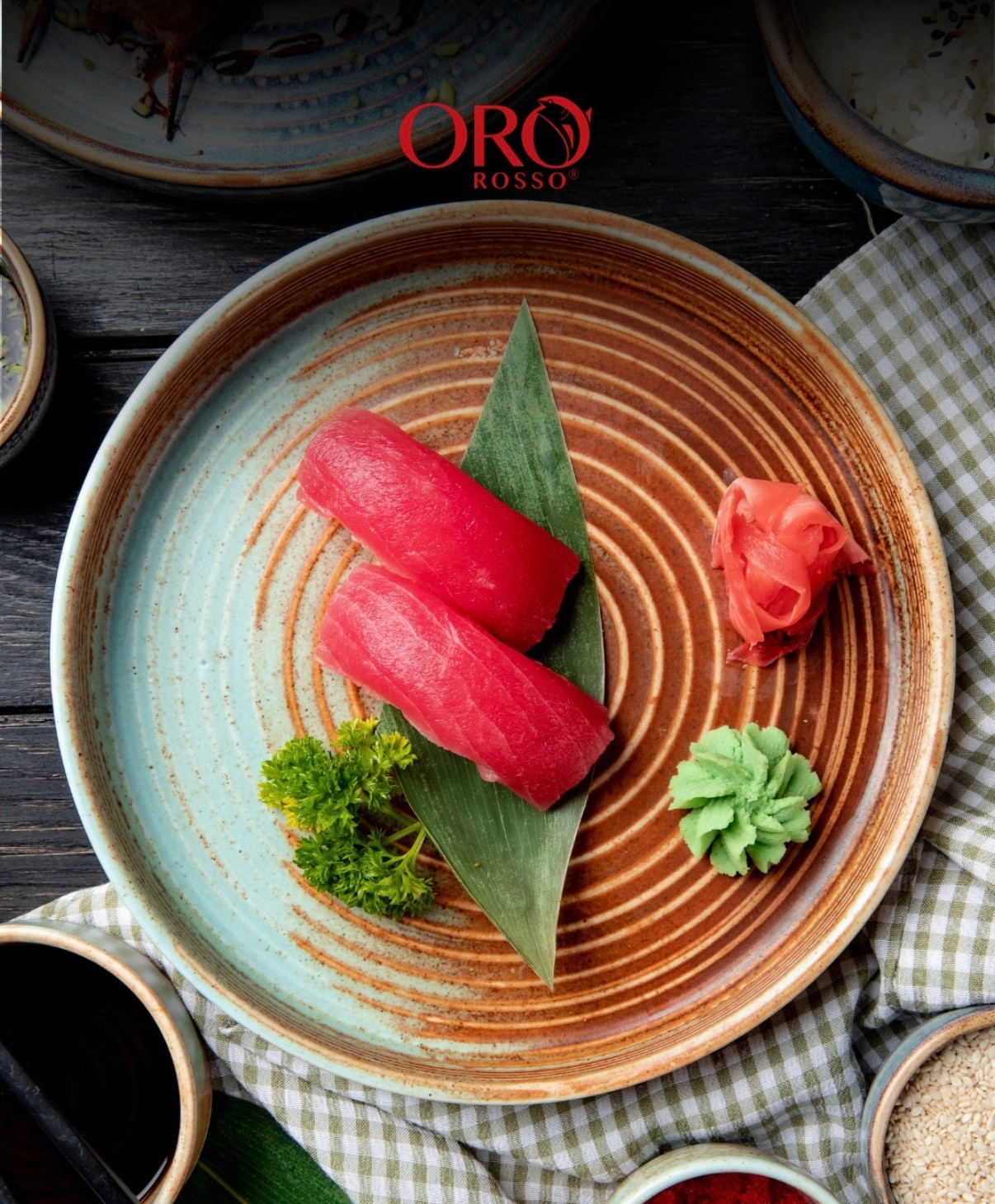 Due nigiri di tonno Oro Rosso su foglia di bambù, con zenzero e wasabi in un piatto di ceramica